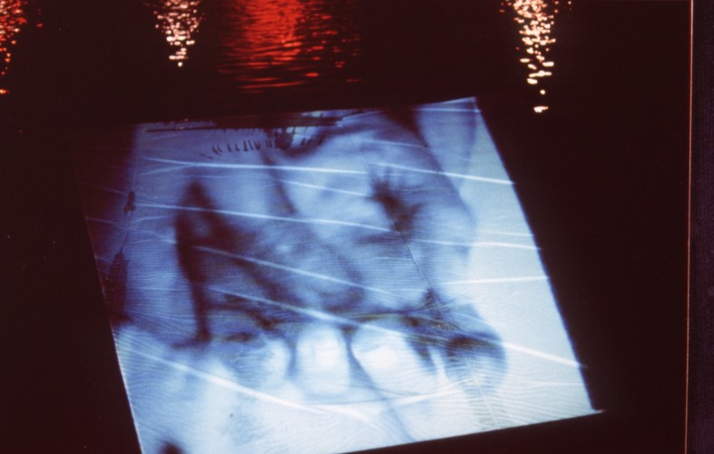 Cotton sheet suspended over lake with projected video of two hands