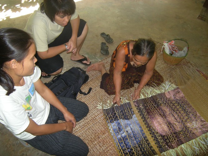 three woman sitting in front of a woven mat